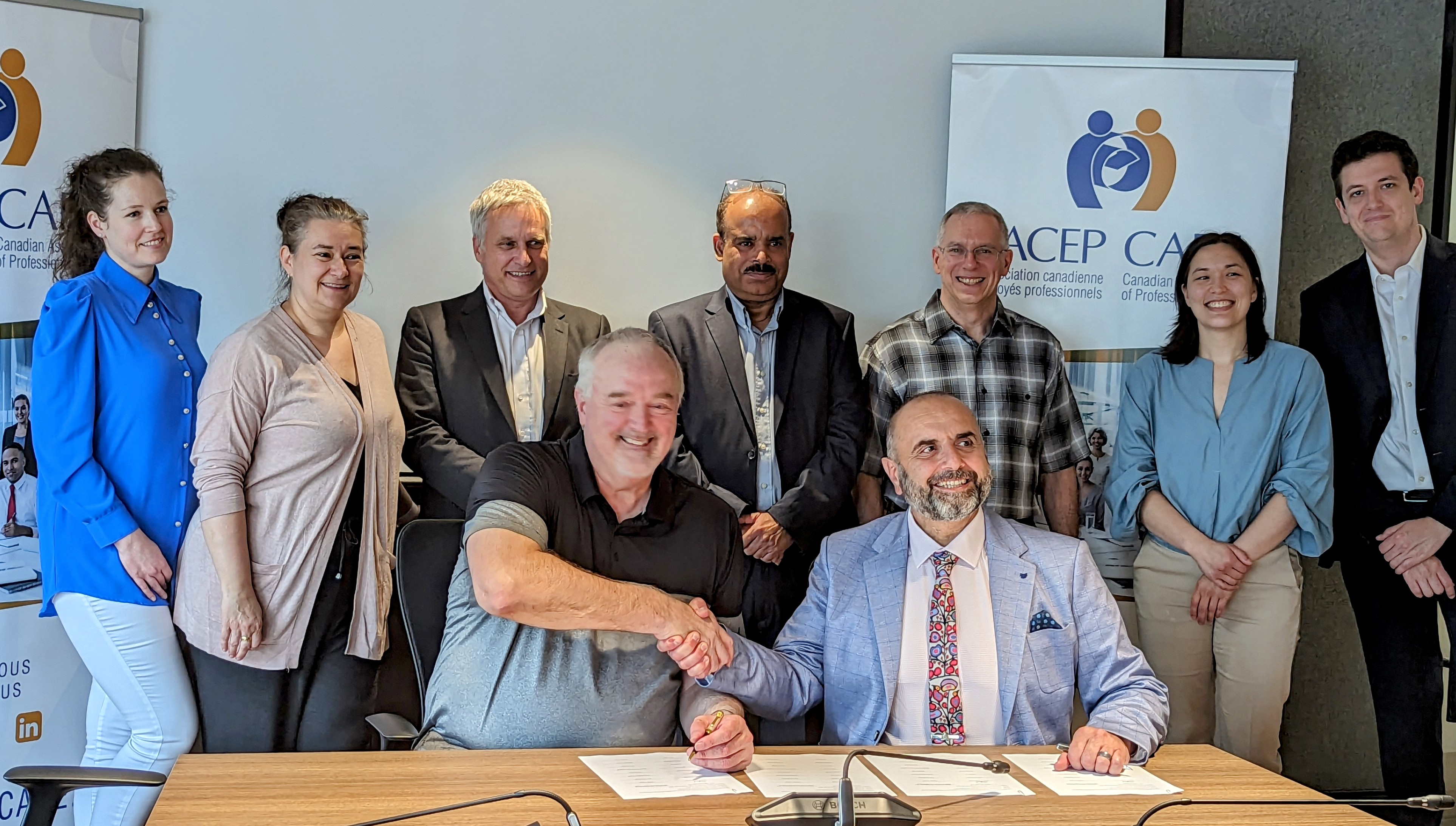 CAPE President Camille Awada seated at table and surrounded by members of the EC bargaining team