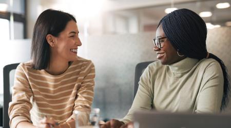 two smiling women sitting in an office